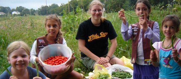Children enjoying a harvest of tomatoes in a community farm field
